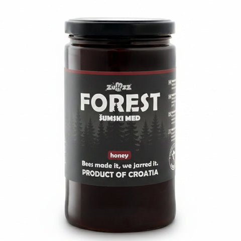 Jar of honey labeled 'Forest' with a black lid on a white background